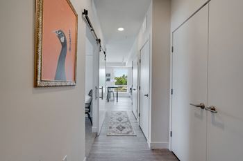 a long hallway with white doors and a painting on the wall